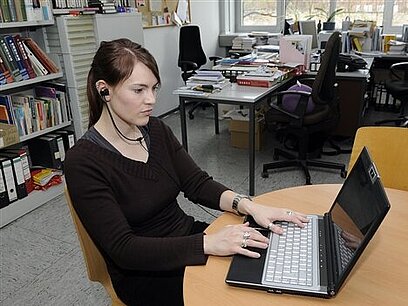 Eine junge Frau arbeitet an einem Laptop.